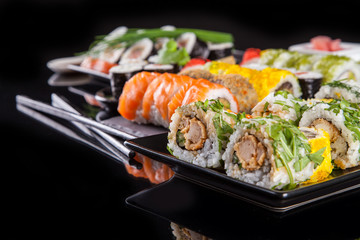 Delicious sushi pieces on black background