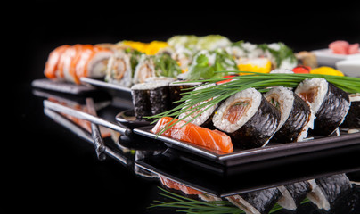 Delicious sushi pieces on black background