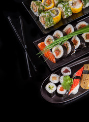 Delicious sushi pieces on black background
