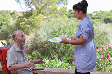 carer giving senior food in residential home