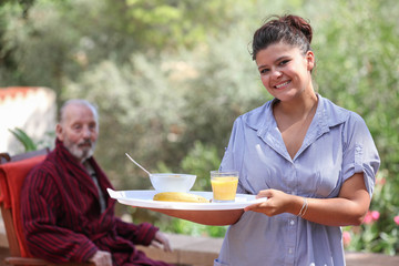 home carer serving meal to elderly man