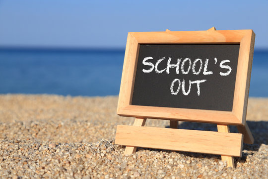 Blackboard with School's out text on the beach