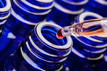 blaue Flaschen mit Pipette und roten Tropfen