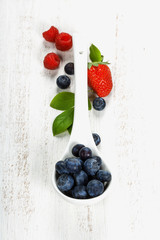 Naklejka na ściany i meble Berries with spoon on Wooden Background.