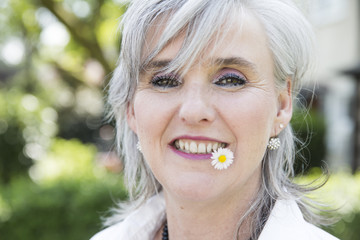 frau,50,grauhaarig,mit gänseblümchen im mund © bilderstoeckchen