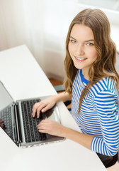 smiling teenage gitl with laptop computer at home