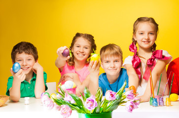 Obraz na płótnie Canvas Four children holding coloured Easter eggs