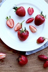 whole strawberries and sliced ​​strawberry on a wooden board
