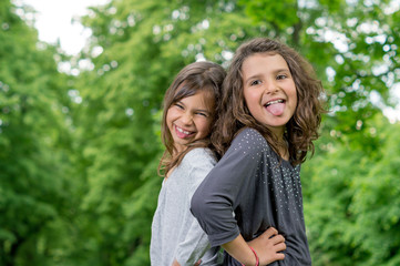 Zwei Mädchen zeigen Zunge im Freien