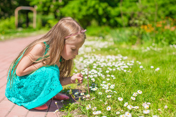 Obraz premium Portrait of adorable little girl blowing a dandelion in the park