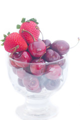 Cherries and strawberry in a glass bowl isolated on white