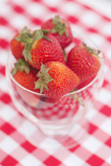 strawberry in a glass bowl on checkered fabric