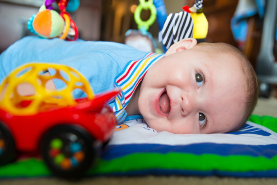 Happy and curious infant baby boy playing on activity mat