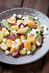 Close-up of fried gnocchi with cheese, meat and arugula leaves