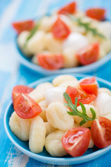 Boiled gnocchi with sliced mozzarella, red tomatoes and arugula