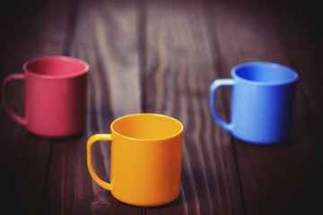 Obraz na płótnie Canvas Three color cups on woodent table.