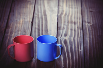 Two color cups on wooden table.