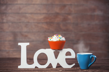 Cupcake, coffee and word Love on wooden table.
