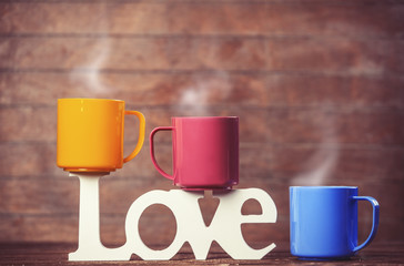 Three cups of coffee and word love on wooden table.