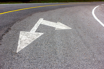 Road arrow direction sign on the asphalt road.