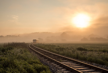 Fototapeta na wymiar Track with the train in misty landscape at sunrise