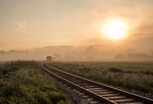 Fototapeta Track with the train in misty landscape at sunrise