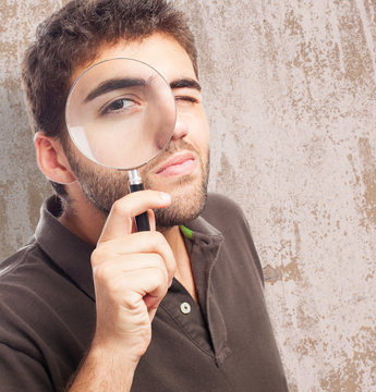 young man looking through magnifying glass