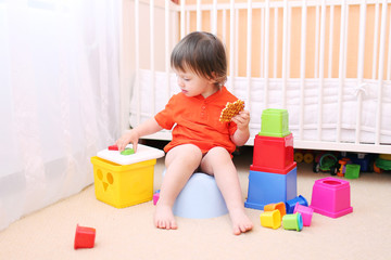 lovely baby plays toys sitting on potty - obrazy, fototapety, plakaty