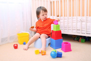 baby boy plays toys sitting on potty