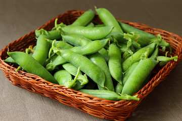 Peas in pods, reclining with a basket.