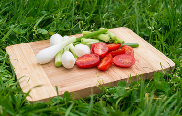 green onions and cherry tomatoes on the old wooden cutting board