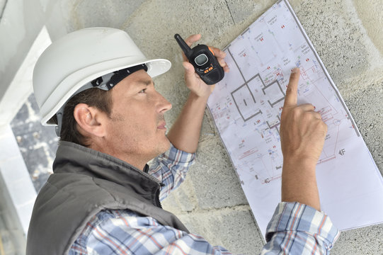 Engineer on building site checking blueprint