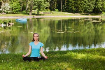Fototapeta na wymiar Beautiful young woman mediteting on coast of wood lake