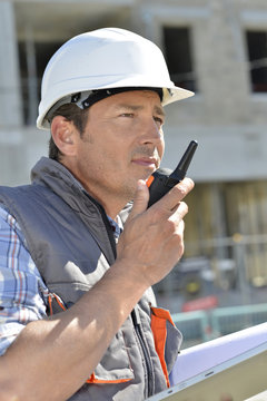 Man on building site using walkie-talkie