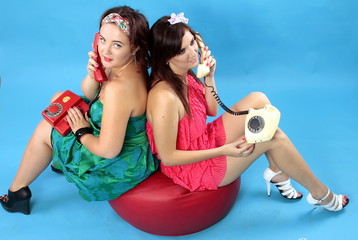 Two young women calling on phones on blue background