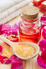 oil in glass bottle, sea salt, towel and rose petals