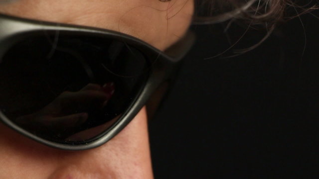 Poker player adjusting his sunglasses with a red chip, close up