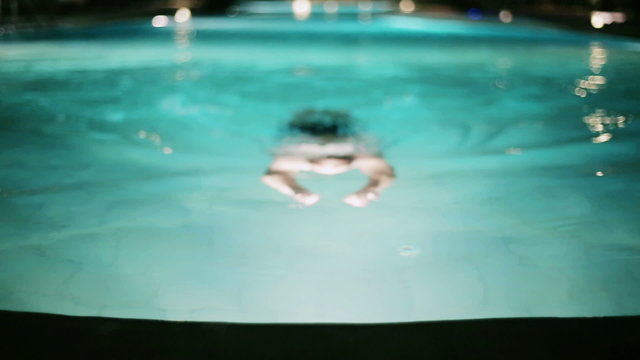 Man swimming in pool at night