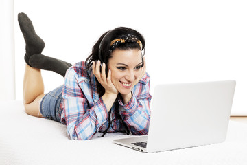 Woman listening to music with headphones and using computer lapt