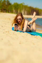 Summer vacation Girl with phone tanning on beach