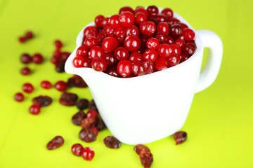 Fresh and dry cranberry in pitchers on wooden table close-up