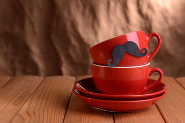 Cup with mustache on table on brown background