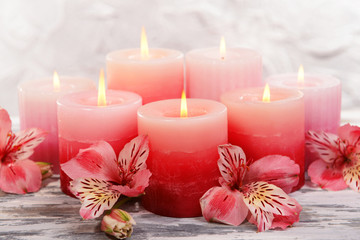 Beautiful candles with flowers on table on grey background