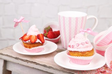 Tasty cup cakes with cream on wooden table