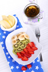 Various sliced fruits on plate on table close-up