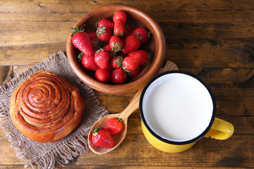 Ripe sweet strawberries in wooden bowl and jug with milk