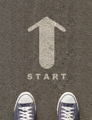 Pair of shoes standing on a road with arrow