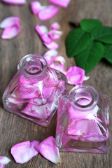 Obraz na płótnie Canvas Rose oil in bottles on color wooden background