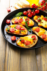 Tasty bruschetta with tomatoes on pan, on old wooden table