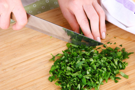 Female hand cutting greens on cutting board